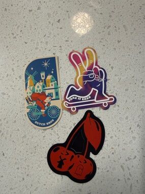 Dutch Bros multicolor peace skate, blue village bike, and red cherry stickers